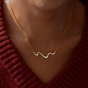 Elegant gold plated S925 silver wavy line necklace with zircon pavé on a red sweater