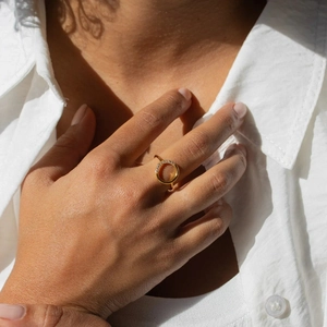 Gros plan d'une bague circulaire plaquée or sertie de zircons sur la main d'un mannequin