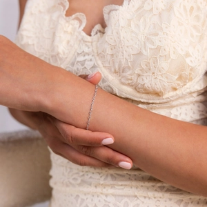Elegant S925 sterling silver heart knot bracelet on female wrist with lace background