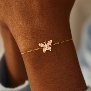Elegant gold butterfly bracelet featuring pink marquise stones on female model wrist