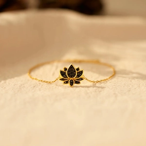 Vue macro d'un bracelet doré avec pendentif lotus noir serti de micro-pierres