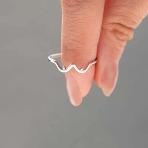 Détail d'une bague vague en argent sterling s925 avec petites perles tenue par les doigts