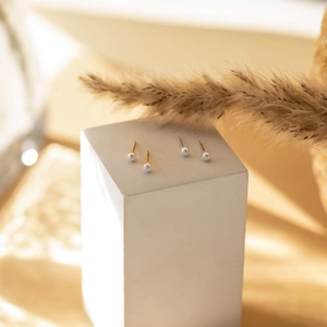 Elegante s925 Sterlingsilber Perlenohrstecker in Gold und Silber auf Stein präsentiert