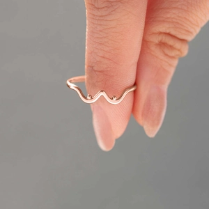 Détail de la bague vague en or rose avec perles symétriques au style minimaliste