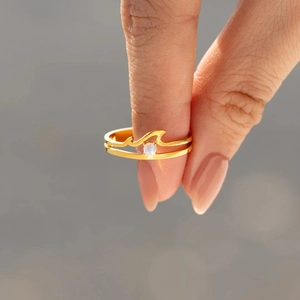 Close-up of gold double-layer wave ring featuring a glowing purple opal gemstone center
