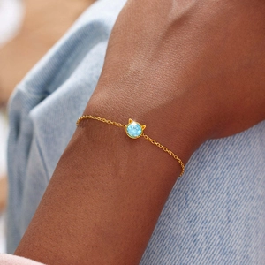 Détail d'un bracelet chat en argent s925 avec zircon bleu sur une chaîne dorée fine