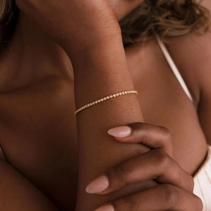 Classic gold tennis bracelet with white cubic zirconia worn on wrist by a model