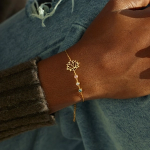 Minimalist gold lotus flower bracelet featuring colorful gemstones on a woman's wrist
