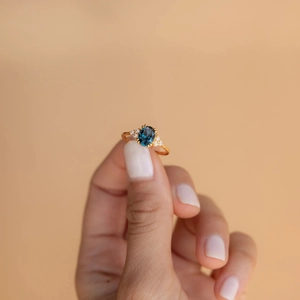 Detailed view of an oval blue gemstone ring with side diamonds on a gold band