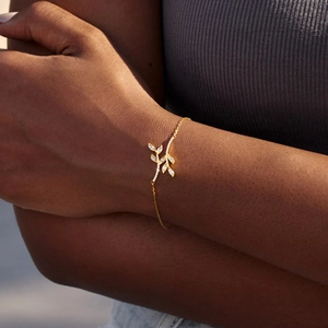 Detailed close-up of golden leaf branch bracelet with small sparkling zircons on wrist