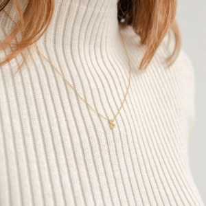 Close-up of a gold S-letter pendant necklace with shimmering crystals on a model