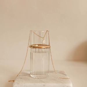 Elegant gold necklace with rectangular links and drop pearl on a minimal glass setup
