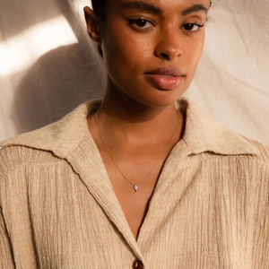 Elegant S925 sterling silver rhombic zircon necklace worn by a model on linen fabric