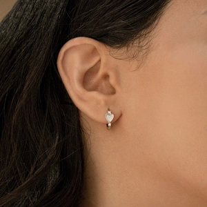 Boucles d'oreilles huggie cœur en argent S925 avec nacre et zircon portées par un mannequin