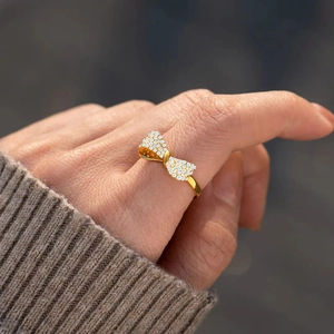 Elegant gold bow ring with full pave zircon stones worn on finger with knit sweater
