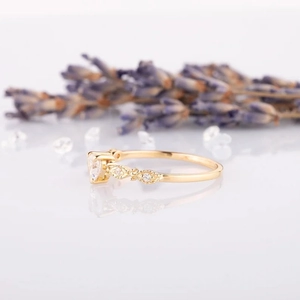 Elegant gold-plated heart ring with sparkling side stones shown against lavender decor