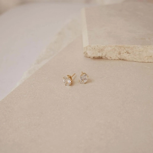 Elegant s925 silver oval zircon stud earrings in gold finish on stone surface
