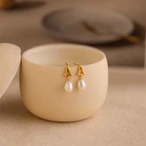 Elegant S925 silver letter A pearl drop earrings hanging on a ceramic jar rim
