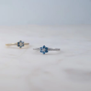 S925 sterling silver flower ring with blue zircons and white center stone on marble