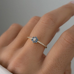 Elegant S925 silver flower ring with blue zircon and pavé diamonds worn by a model