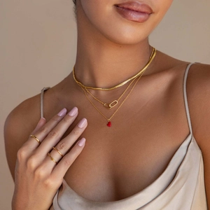 Colliers dorés superposés avec pendentif cœur rouge et bagues minimalistes assorties