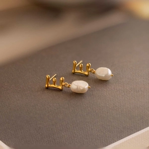 Macro detail of gold molten-style metal earrings with elegant baroque white pearls