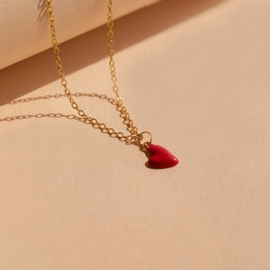Collier en argent S925 doré avec pendentif cœur en émail rouge sur présentoir beige
