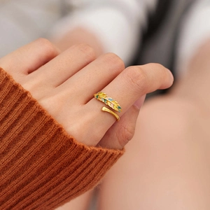 Détail d'une bague plume dorée ajustable avec émail coloré sur le doigt d'une femme