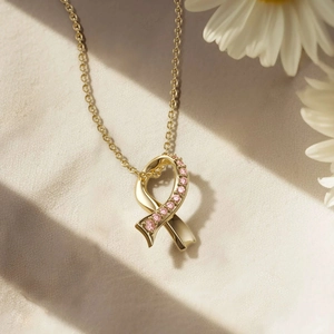 Collier ruban croisé en argent s925 doré avec gemmes roses sur fond de tissu beige