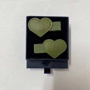 Detail of green leather heart bookmarks with decorative stitching in a blue gift box