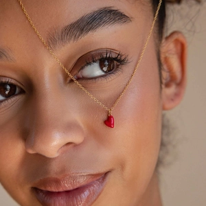 Détail artistique du collier s925 doré avec un pendentif cœur en émail rouge brillant