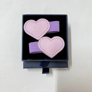 Detail of two purple heart magnetic bookmarks with stitching in a blue velvet gift box