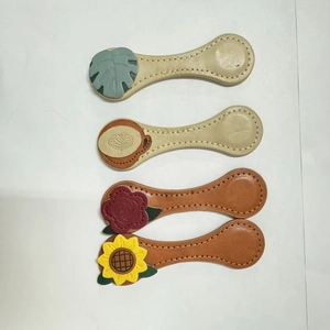 Detail of vintage leather magnetic bookmarks with floral and leaf stitching designs