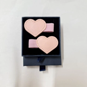 Close-up of pink heart-shaped faux leather hair clips with pen loop in a gift box