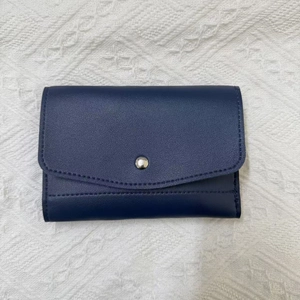 Detail of navy blue lychee leather jewelry roll with silver metal button and fine stitching