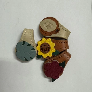 Close-up of magnetic leather bookmarks featuring sunflower, rose, and coffee cup designs