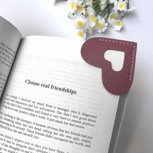 Burgundy heart-shaped leather corner bookmark with cutout on an open book page