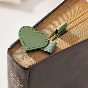 Green leather heart magnetic bookmark with pen loop holder on vintage book pages
