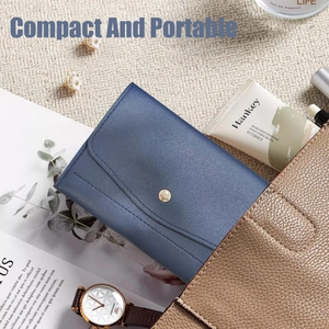 Blue leather travel jewelry roll organizer being placed into a stylish handbag