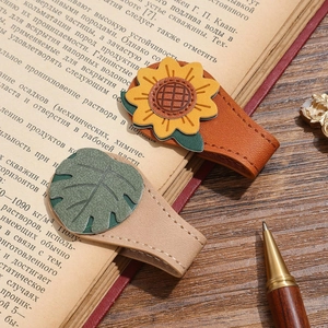 Detailed view of vintage leather bookmarks featuring sunflower and leaf designs on an open book