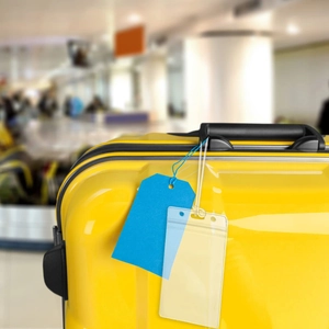 Detail of waterproof transparent PVC luggage tag on a yellow suitcase for travel