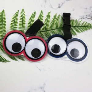 Red and blue luggage tags with googly eye design and adjustable black straps on marble