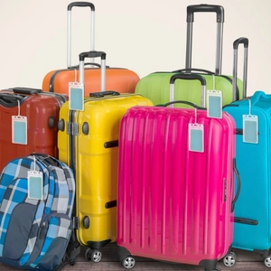 Detail view of colorful PVC luggage tags attached to a set of multi-colored travel suitcases