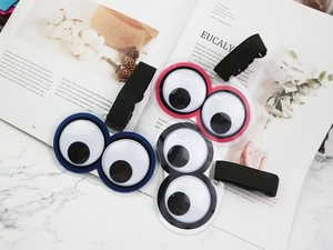 Three colorful googly eyes hair ties on marble background with magazine, vibrant lifestyle shot