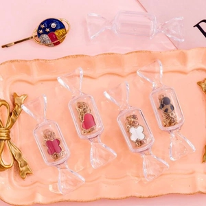 Détail de boîtes à bijoux en forme de bonbon avec breloques trèfle et cœur sur plateau