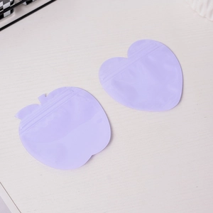 Purple heart and apple shaped PVC frosted resealable pouches on a light wood background