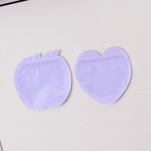 Translucent purple apple and heart shaped frosted PVC resealable pouches on wood