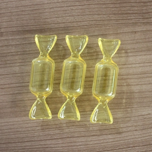Trois boîtes à bijoux transparentes en forme de bonbon jaune sur une table en bois