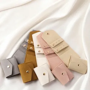 Micro-velvet jewelry pouches in five colors with gold snap buttons on white silk background