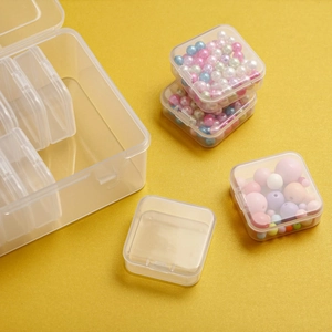 Macro view of clear plastic organizer box showing small square compartments for beads